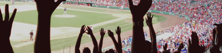Photo of hands raised, cheering at a baseball game.